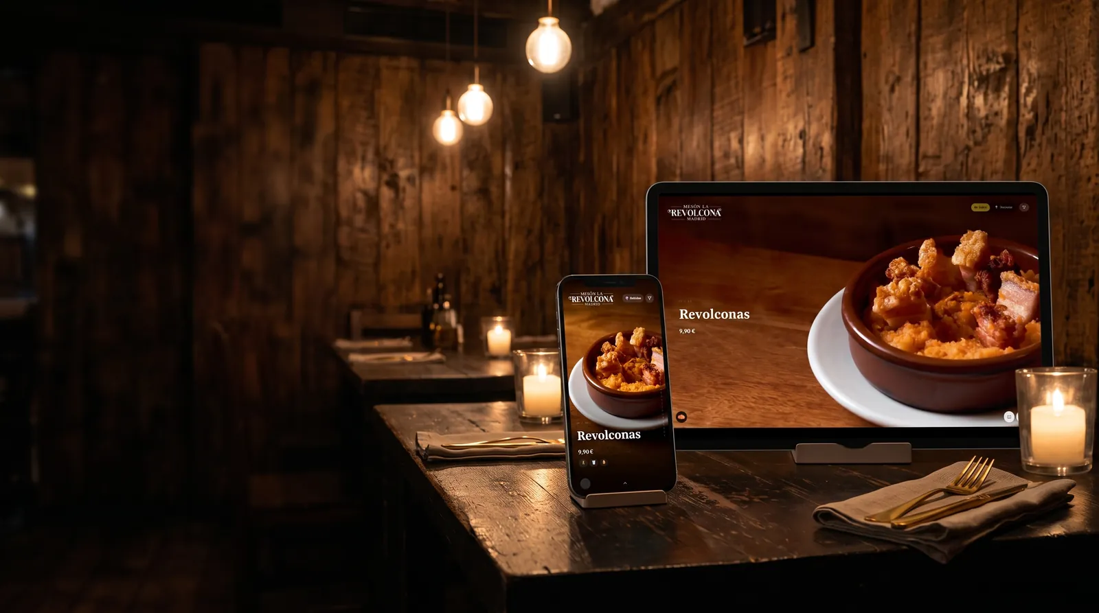 Tablet y móvil con la carta digital de un mesón sobre una mesa de madera, a la luz de una vela